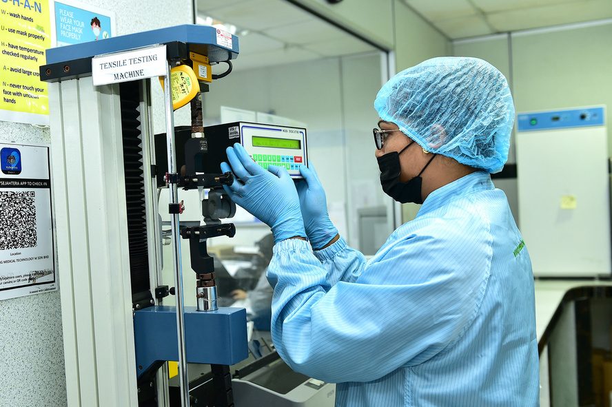 Technician performing tensile testing on gloves in the laboratory