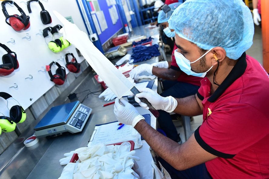 Quality control inspector checking and weighing gloves on the line