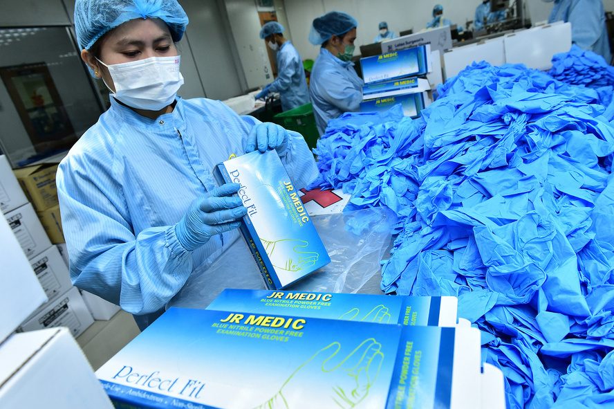 Worker packing blue nitrile examination gloves into dispenser boxes