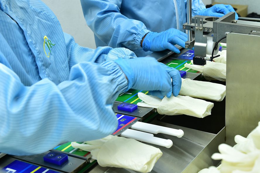 Operators packing sterile surgical gloves on a cleanroom line